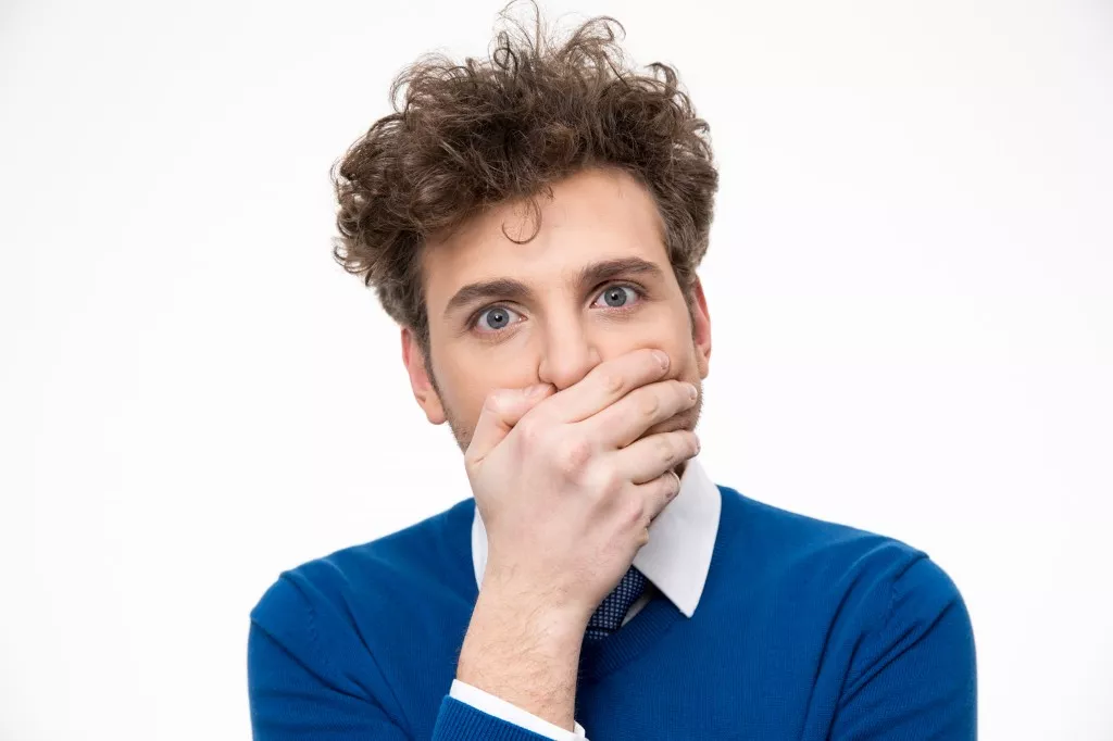 Handsome man covering his mouth over white background